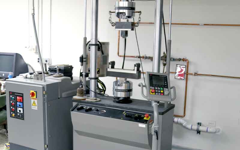 one gray machinery with red, blue, green buttons, one rectangle machinery with buttons and metal beams for testing rigs